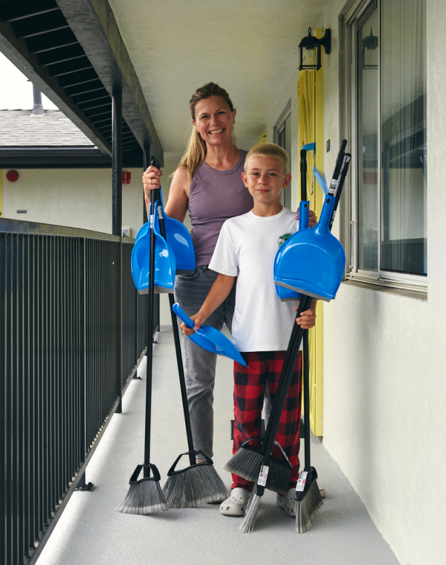 Volunteers posing with brooms at the Allgire Foundation volunteer day