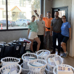 Volunteers posing in front of baskets of supplies