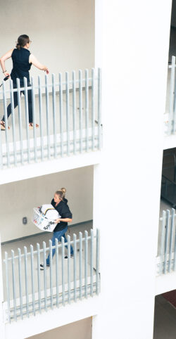 Photograph of people walking in an apartment on two different levels