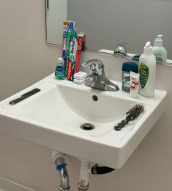Photograph of a bathroom sink with fresh toothbrushes and cleaning supplies