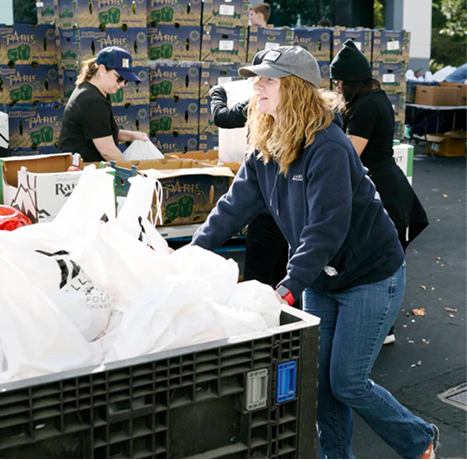 Volunteers pushing a cart of produce