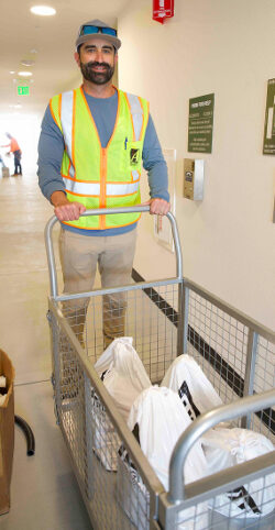A man in a yellow safetly vest pushing a cart full of Allgire Foundation welcome kits